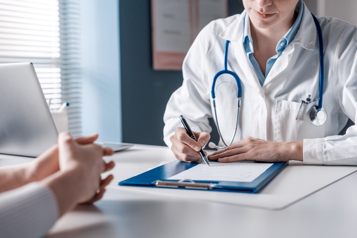 doctor taking medical notes while meeting with patient