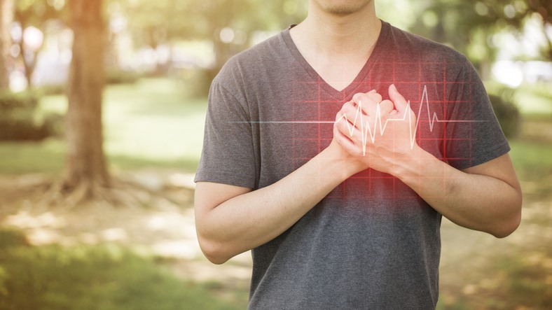 Close up of man holding hand over heart indicating heart attack