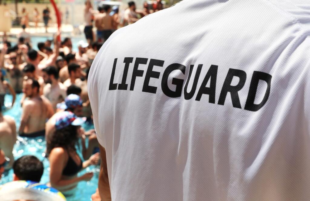 The back of a lifeguard at a populated pool.