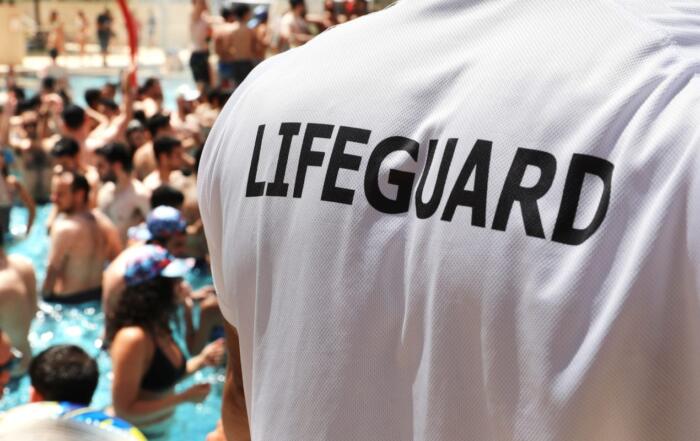 The back of a lifeguard at a populated pool.