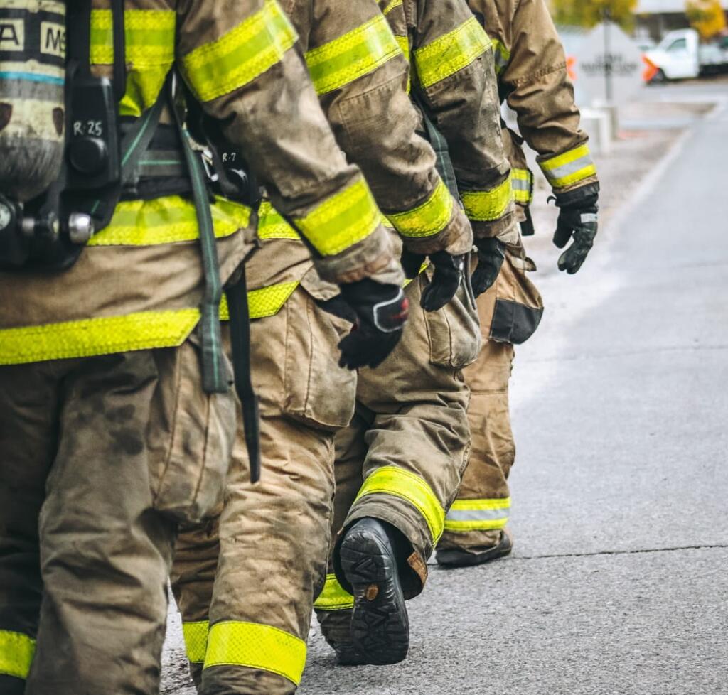 Four firefighters in a row, walking together.