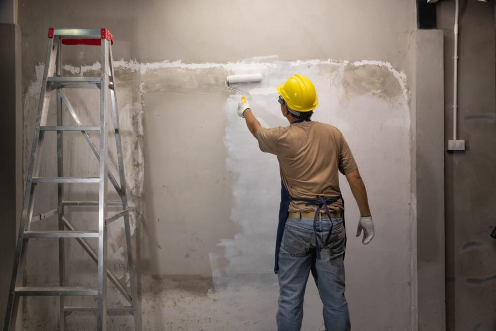 A construction painter painting a wall inside a new home.