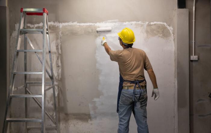 A construction painter painting a wall inside a new home.