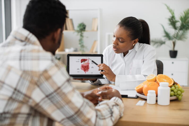 A doctor going over test results with a patient, showing them images on a tablet.