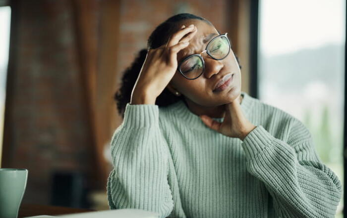 A Woman With Her Eyes Closed Holds Her Head And Neck As She'S Overcome With Stress.