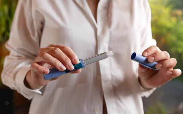 Blog 2 A Woman In A White Shirt Is Holding A Semaglutide Injection Pen In Her Hands.